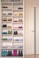 Empty domestic wardrobe interior with many female shoes neatly folded on shelves of cupboard