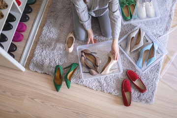Female hands pack shoes on heels into plastic box home wardrobe storage method organization top view