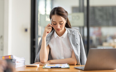 Portrait of tired young business Asian woman work with documents tax laptop computer in office. Sad, unhappy, Worried, Depression, or employee life stress concept