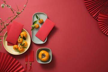 Fruits, lucky money, paper fan, and Lucky envelopes on a red background. Empty space for text. Chinese lunar new year. Top view