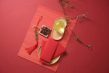 Lucky envelopes, tea, and lucky ornament on red bamboo blinds. Chinese Lunar New year background....
