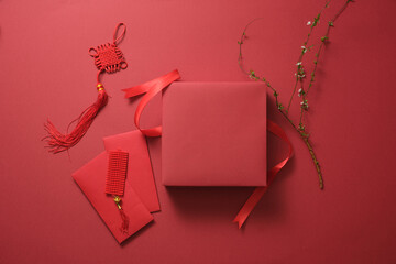 Top view of lucky ornaments, red envelopes, and gift box on the red background. Chinese new year...