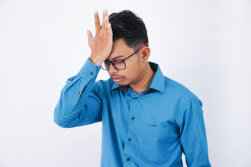 Handsome young asian businessman with glasses in wearing blue shirt forgetting something, slapping...