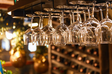 A lot of crystal clear clean wine glasses placed on top rack of a bar table inside a wine pub....