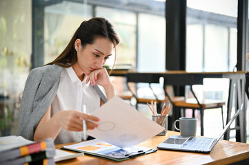 Professional and stressed Asian businesswoman reading a financial report