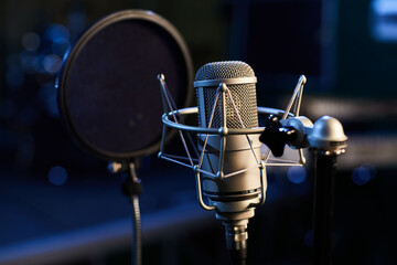 Microphone with a pop shield closeup on the background of a professional recording studio....