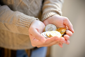 A female's hands holding golden and silver bitcoins. close-up image, investment, saving money