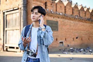 Asian male traveler or tourist talking on the phone while strolling around the old city.