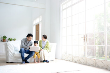 Image of an Asian family laughing in the living room while looking at the computer(laptop)