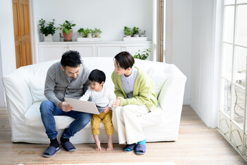 Fototapeta premium リビングにて家族でパソコンを覗いているイメージ