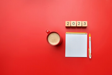 A pen, a notebook, a cup of coffee and the inscription: 2023. Making plans and goals for the new year