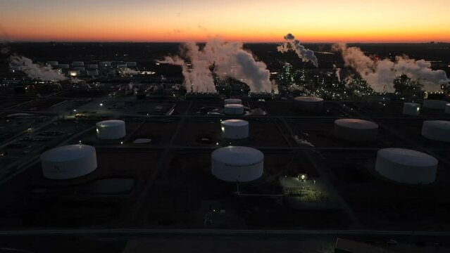 Silhouette of oil refinery and fuel storage tanks. Gasoline and fuel price theme in USA. American energy production. Aerial at sunrise.