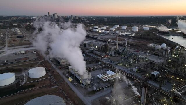 Oil refinery in Tulsa Oklahoma. Aerial view of fuel tanks and skyline at sunrise. Aerial pullback reveal.