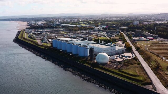 Aerial shot approaching a sewage plant by the sea on the outskirts of Edinburgh on a sunny day