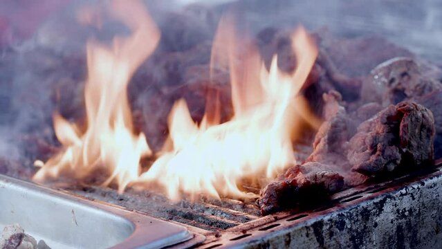 Thick, whitish steam covering delicious, organic food, turning by the cook. Close-up shot of roasted, red meat cooking on open fire barbecue grill. High quality 4k footage