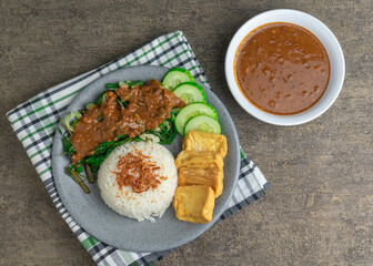 nasi pecel is traditional Indonesian javanese salad with peanut sauce. serve with steam rice, fried tofu, and cucumber