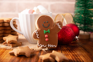 Christmas Homemade gingerbread man cookie and white cup with hot chocolate with marshmallows, traditionally made at wintertime and the holidays.