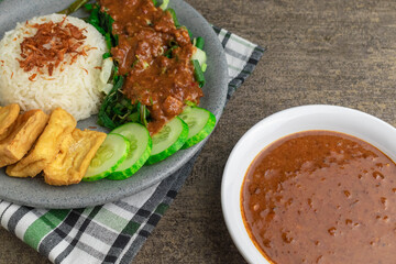 nasi pecel is traditional Indonesian javanese salad with peanut sauce. serve with steam rice, fried tofu, and cucumber