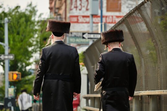 a hasidic jewish man walking down the street in williamsburg brooklyn
