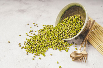 fresh mung beans in ceramic dishes against a white stone background, coppy space.