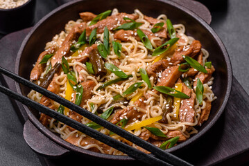 Tasty dish of Asian cuisine with rice noodles, chicken, asparagus, pepper, sesame seeds and soy sauce