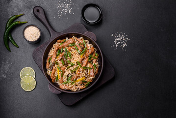 Tasty dish of Asian cuisine with rice noodles, chicken, asparagus, pepper, sesame seeds and soy sauce