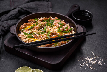 Tasty dish of Asian cuisine with rice noodles, chicken, asparagus, pepper, sesame seeds and soy sauce