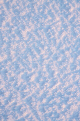 Natural snow texture. The surface of an icy snow crust. Snowy ground. Winter background with snow patterns. Perfect for Christmas and New Year design. Closeup top view.