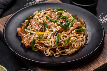 Tasty dish of Asian cuisine with rice noodles, chicken, asparagus, pepper, sesame seeds and soy sauce