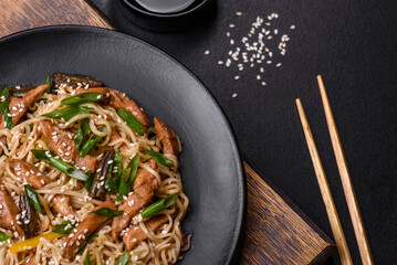 Tasty dish of Asian cuisine with rice noodles, chicken, asparagus, pepper, sesame seeds and soy sauce