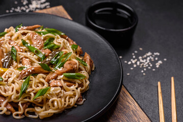 Tasty dish of Asian cuisine with rice noodles, chicken, asparagus, pepper, sesame seeds and soy sauce