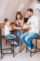 Happy family playing chess in the kitchen