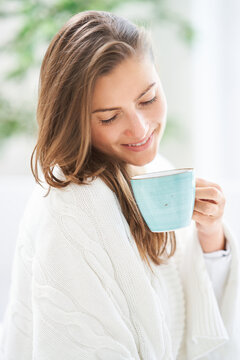Young nice woman in bed with coffee or tea mug