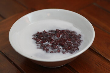 a bowl of black sticky rice porridge with coconut milk