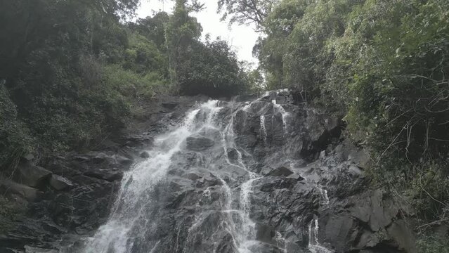 Beautiful view of a waterfall from rocks in a forest with trees