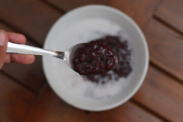 a bowl of black sticky rice porridge with coconut milk