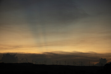 Silhouettes of Wind turbines farm on mountains in rural areas with Colorful scenery skyline background.