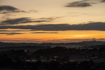 Morning view at morning sunrise, clouds in orange crimson colors. Silhouettes of houses roofs, trees, and a monastery on the hill. Colorful scenery skyline background.