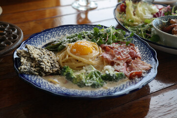 Pasta dish with vegetables and bacon on an antique plate