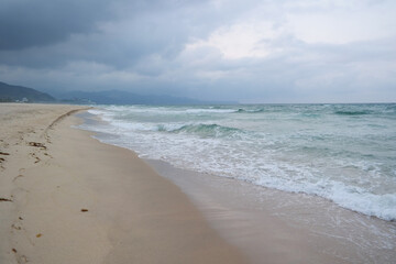 Fototapeta na wymiar Waves crashing on a cloudy sandy beach