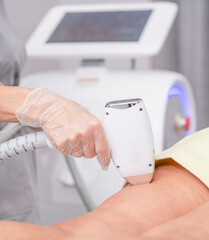 Professional beautician removes hair on female buttocks of senior woman using a laser. hair removal...
