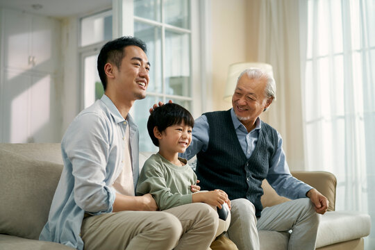 asian son father grandfather watching soccer game on TV together at home