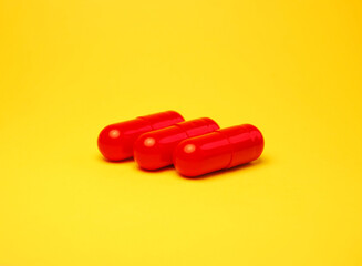 A group of red capsules isolated on bright yellow background
