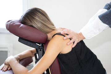 Massage therapist woman massaging female back sitting on massage seated on knee massage chair...
