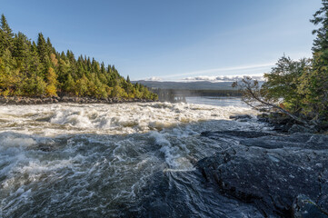 Famous waterfall Tannforsen northern Sweden, with a rainbow in the mist and rapid flowing cascades of water