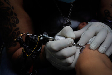 Persona realizando un tatuaje profesional en el antebrazo con tinta negra a detalle