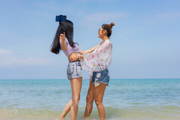 Two girlfriends hugging up and enjoying on the sea beach. A pair of girls in love cuddling on a tropical beach. romantic young lesbian couples in love and walking together on the beach.Concept of LGBT