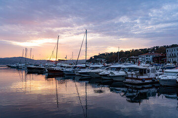 Fototapeta na wymiar Sailboats at Tarabya yacht marina in Istanbul. Reflection of yachts and hotel. Blue sky and natural white clouds. 