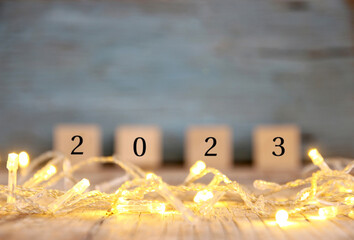 blurred happy new year 2023 on wood table and blur abstract bokeh light