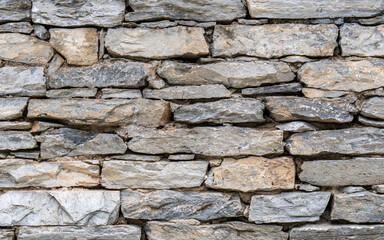 A stonewall made with gray granite slabs cut to various sizes.